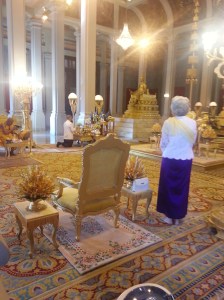Sa Majesté la Reine-Mère recueillie pendant que Sa Majesté le Roi allume les baguettes d'encens de l'autel royal
